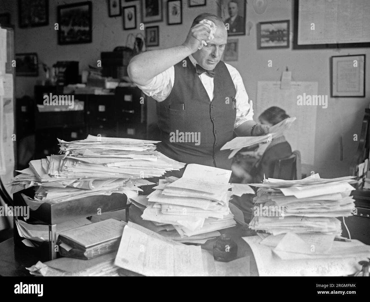 roy-g-fitzgerald-standing-behind-a-very-messy-desk-wiping-his-perspiring-forehead-ca-1923-2RGMFMK